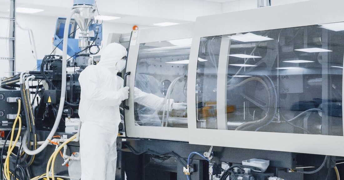Scientist in Protective Clothing working on Modern Industrial Machinery.
